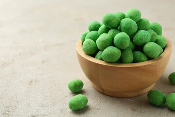 Wasabi coated peanuts in bowl on light table, closeup. Space for text