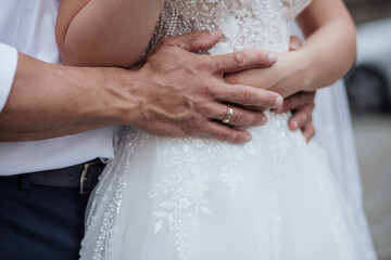 Groom hands embracing bride waist, closeup view