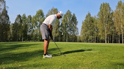 Golf player practicing swing on a sunny day in a lush green golf course