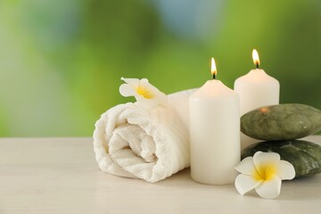 Beautiful spa composition with burning candles on white wooden table against blurred background, closeup. Space for text