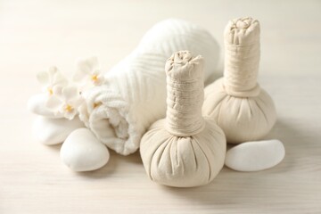 Beautiful spa composition with herbal bags on white wooden table, closeup