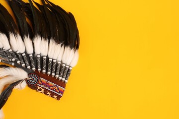 Traditional warbonnet (Native American chief headdress) on yellow background, top view