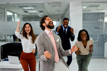 Diverse corporate colleagues cheer with joy in office after achieving success