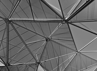 Obraz premium monochrome view of geometric interweaving of poles and canvas against the sky