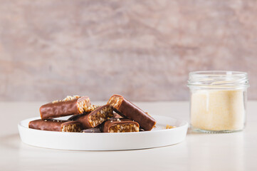 Protein bars with nuts on plate and protein powder in jar on table