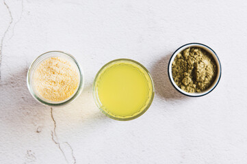 Close up of matcha protein drink in a glass and powders on the table top view