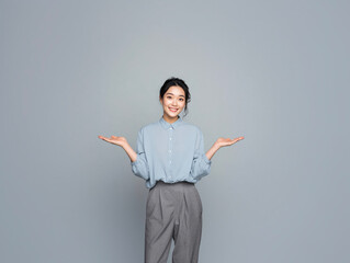 Young Asian businesswoman with open palms presenting gesture on gray studio background professional corporate portrait