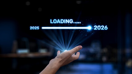 A hand reaches towards a glowing loading bar indicating the transition from 2025 to 2026. This image embodies themes of progress, technology, and anticipation of the future. Synapse