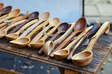 A rustic display of handmade wooden spoons in various shapes and sizes arranged neatly on a wooden table in a traditional craft market