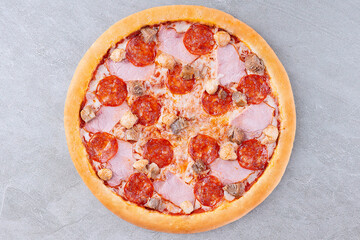 Meat Lovers Pizza with Pepperoni, Ham, Sausage, and Beef Toppings on Golden Crust over Gray Stone Background