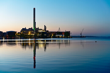 Flensburg metal works at dusk with green lit chimney
