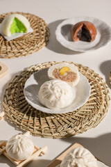 A variety of steamed buns displayed on woven mats, showcasing different fillings and colors, highlighting their intricate designs and appetizing appearance.
