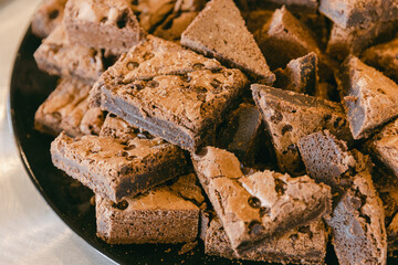 Decadent chocolate brownies stacked on a black plate at a cozy bakery setting during afternoon hours