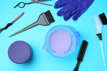 Care cosmetic product for blonde hair in bowl and hairdresser's tools on light blue background, flat lay