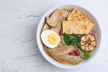 Tasty ramen with enoki and king oyster (eryngii) mushrooms on white table, top view. Space for text