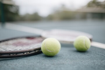 Two tennis balls and a racket are on a court