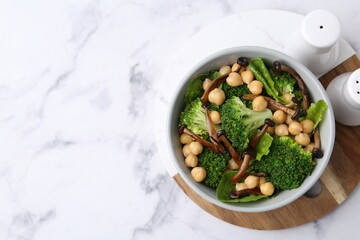 Delicious salad with shimeji mushrooms, chickpeas and broccoli in bowl on white marble table, top view. Space for text