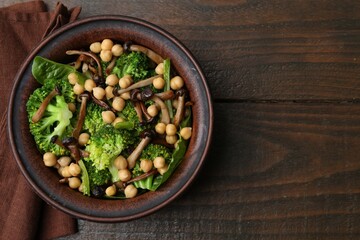 Delicious salad with shimeji mushrooms, chickpeas and broccoli in bowl on wooden table, top view. Space for text