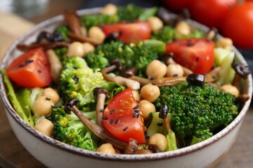 Delicious salad with shimeji mushrooms, chickpeas, tomatoes and broccoli in bowl on table, closeup