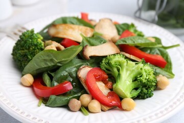 Tasty salad with eryngium mushrooms, chickpeas, vegetables and spinach on table, closeup