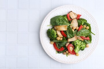 Tasty salad with eryngium mushrooms, chickpeas, vegetables and spinach on white tiled table, top view. Space for text