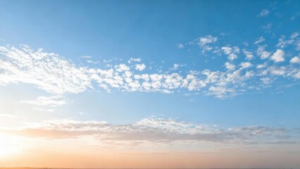 A wide-view shot of a serene sky filled with scattered clouds, bathed in the soft hues of a golden...