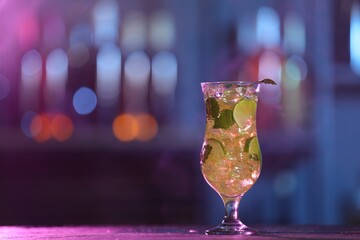 Glass of alcoholic cocktail on table against blurred background, space for text