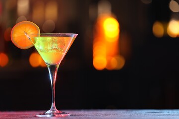 Glass of alcoholic cocktail with garnish on table against blurred background, space for text. Bokeh effect