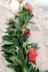 Beautiful floral centerpiece with greenery for a wedding reception table setting in the evening