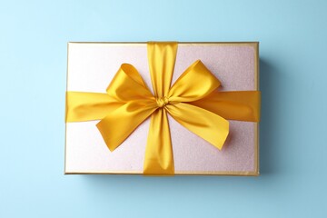Gift box with beautiful bow on light blue background, top view