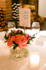 Beautiful floral centerpiece on table number seven at a warm event setting with wine bottles in the background