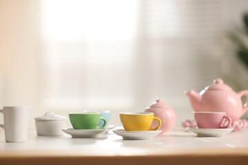 Tea set on white table indoors, closeup with space for text. Child's toy