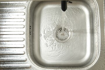 Water flowing from tap into sink, top view