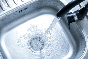 Water flowing from tap into sink, above view