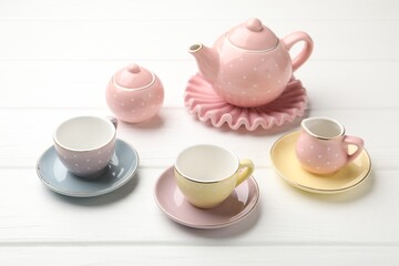 Beautiful ceramic tea set for children on white wooden table, closeup