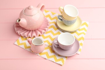 Beautiful ceramic tea set for children on pink wooden table