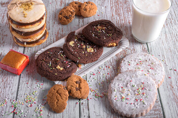 Assorted cookies with chocolate and sugar, decorated with sprinkles and served with a glass of milk, sweet dessert for holidays and celebrations