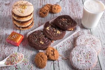 Assorted cookies with chocolate and sugar, decorated with sprinkles and served with a glass of milk, sweet dessert for holidays and celebrations