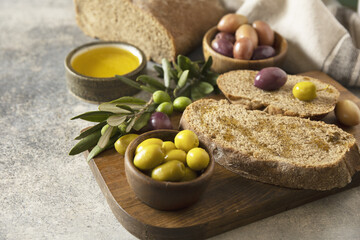 Mediterranean snack with mixed olives, olive oil, and rustic bread on wooden board
