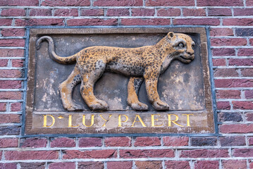 Antique facing brick with a leopard sculpture and name D'Luypaert (Leopard) on the exterior wall of an old house in the historic center of Amsterdam, Holland, The Netherlands, Europe