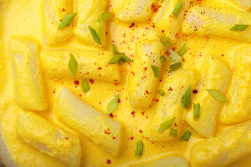 Close up of traditional korean tteokbokki in creamy cheese sauce with garnish, top view, authentic food of Korea