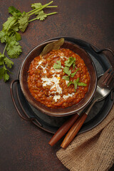 Dal makhani with cream and coriander leaves served in rustic bowl, accompanied by spices such as turmeric, cinnamon, and star anise, authentic Indian dish