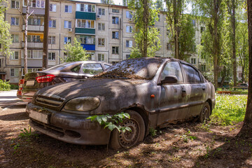 Abandoned car overgrown with foliage in urban setting