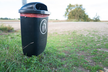 Plastic, general waste and dog poo bin seen at the entrance to a public bridle way in the UK. The bin features the standard, generic litter symbol.