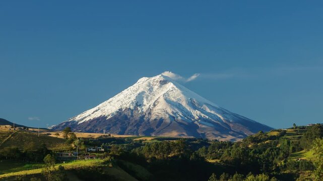 Time-lapse of Ecuador's iconic Cotopaxi volcano rising majestically under a blue sky, crowned by its glacier and emitting a fumarole of steam.