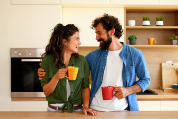 Happy couple enjoying morning coffee together in modern kitchen