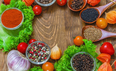 Cherry tomatoes, garlic, wooden spoons, herbs and spices on wooden background. Home cooking concept.