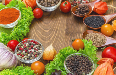 Cherry tomatoes, garlic, wooden spoons, herbs and spices on wooden background. Home cooking concept.