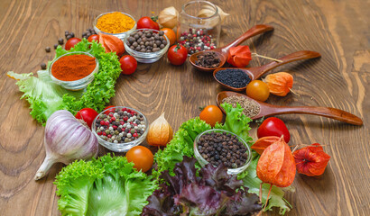 Arrangement of bright spices and vegetables red tomatoes, garlic, physalis on textured wooden board.
