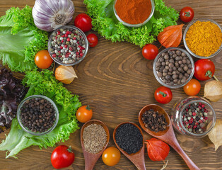 Variation of bright spices and vegetables red tomatoes, garlic, physalis on textured wooden board.